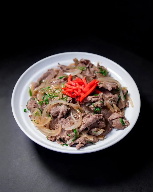 Prato de carne fatiada com cebola e acompanhamentos do O Quinto Sabor