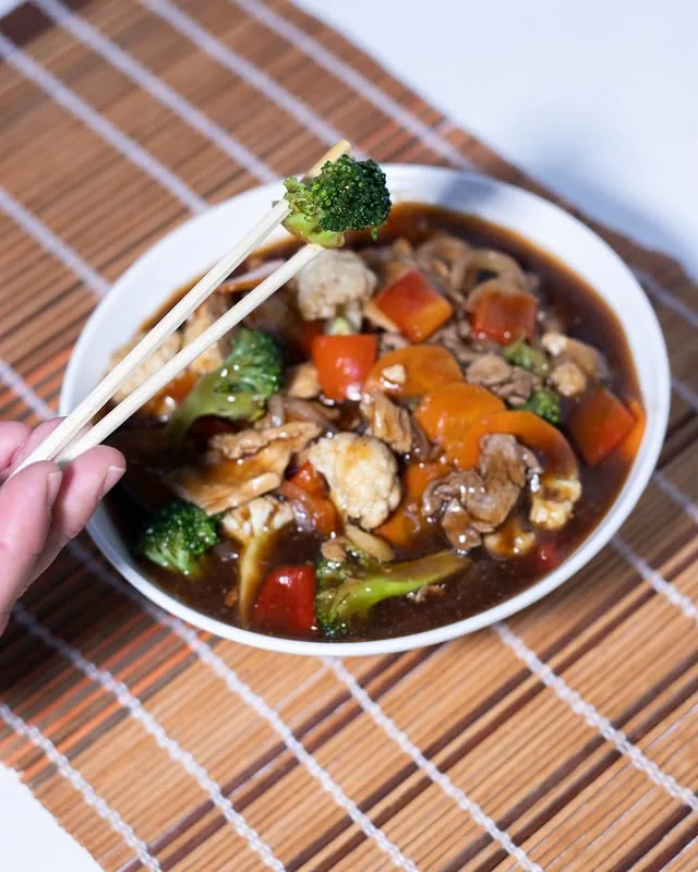 Yakisoba sendo servido de uma tigela com hashi